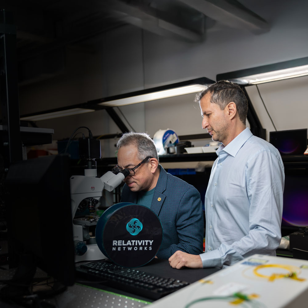 Jason and Rodrigo in a technical room, one looking into a microscope