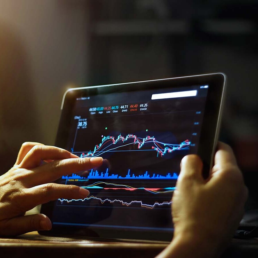 Hands holding a tablet with a financial graph